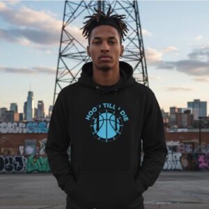 Man in a black hoodie stands in an urban setting with city skyline in the background.