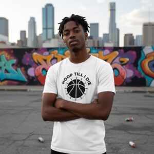 Young man in a white basketball shirt standing with arms crossed outdoors.